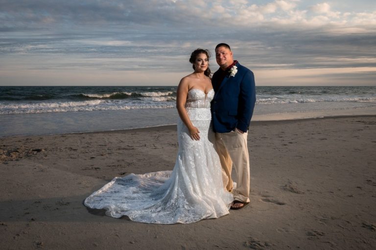 A wedding couple on the beach dressed up with dynamic sky