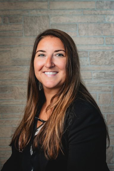 Headshot of a woman with tan brick background