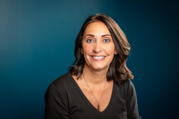 Headshot of a woman with a teal background