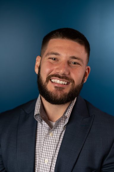 Headshot of a man with a blue background