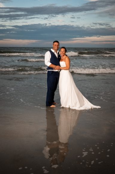 A couple on the beach in formal attire with a dramatic sky.