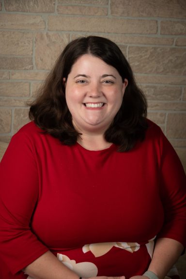 Headshot of a woman with tan brick background