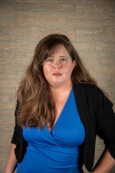 Headshot of a woman with tan brick background