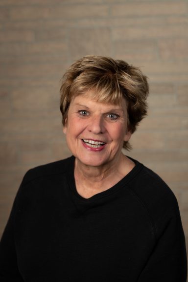 Headshot of a woman with tan brick background