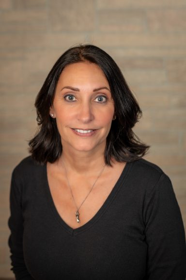 Headshot of a woman with tan brick background